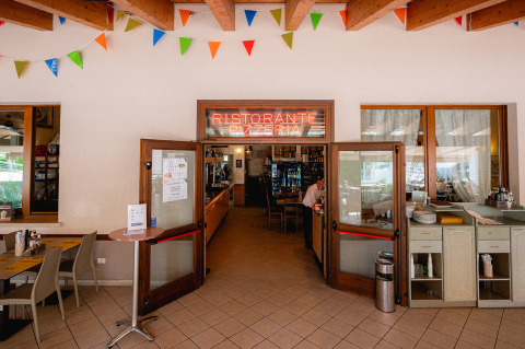 Entrada a un restaurante italiano con banderines de colores en Camping Village Cavallino, Véneto, Italia.