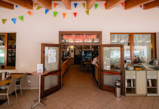 Indgang til en italiensk restaurant med farvede flag og skilte, Camping Village Cavallino, Veneto, Italien.