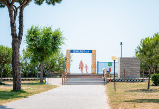 Indgangen til Baia Beach ved Camping Village Cavallino, med to personer der går mod stranden i Veneto, Italien.