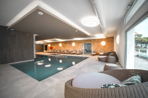 Piscina coperta con lettini e sedute in rattan al Camping Village Cavallino, Veneto, Italia.