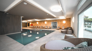 Zona de piscina cubierta con tumbonas y asientos de mimbre en Camping Village Cavallino, Véneto, Italia.