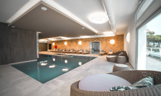 Zona de piscina cubierta con tumbonas y asientos de mimbre en Camping Village Cavallino, Véneto, Italia.