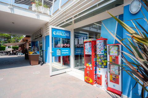 Entrada al Camping Village Cavallino en Véneto, Italia, con máquinas expendedoras y fachada azul.