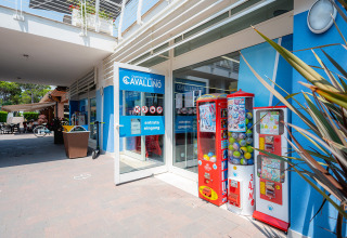 Ingresso del Camping Village Cavallino in Veneto, Italia, con distributori automatici e parete blu.