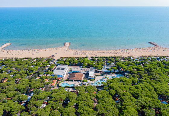 Luftfoto af Camping Village Cavallino i Veneto, Italien, med poolområde, grønne træer og strand.