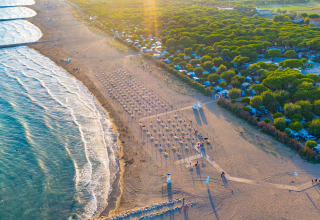 Vista aerea del Camping Village Cavallino in Veneto, Italia, con spiaggia, mare e campeggio al tramonto.