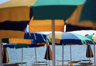 Sillas de playa y sombrillas de colores junto al mar en Centro Vacanze Isuledda, un parque vacacional en Cerdeña.