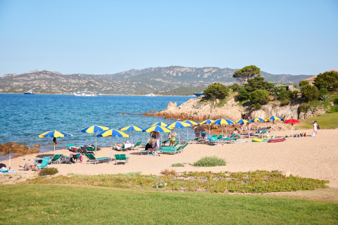 Scène de plage avec parasols et transats au Centro Vacanze Isuledda, village vacances en Sardaigne, Italie.