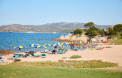 Scène de plage avec parasols et transats au Centro Vacanze Isuledda, village vacances en Sardaigne, Italie.