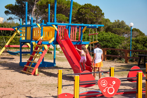 Kinderen spelend op een kleurrijke speeltuin in Centro Vacanze Isuledda, vakantiepark op Sardinië, Italië.