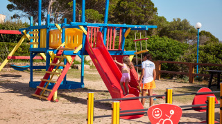 Niños jugando en un colorido parque infantil en Centro Vacanze Isuledda, un parque vacacional en Cerdeña.