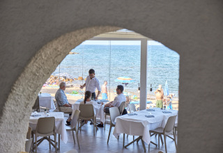 View of guests dining at a seaside restaurant in Centro Vacanze Isuledda holiday park, Sardinia, Italy.