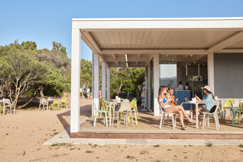 Cafetería al aire libre en Centro Vacanze Isuledda, parque vacacional en Cerdeña, Italia, con visitantes.