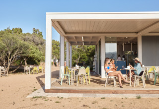Udendørs café ved Centro Vacanze Isuledda feriepark i Sardinien, Italien, med gæster og solskin.