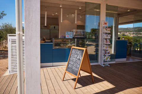 Un café moderne au Centro Vacanze Isuledda en Sardaigne, Italie, avec ardoise et vitrine en verre.
