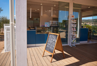 Een modern café aan Centro Vacanze Isuledda op Sardinië, Italië, met stoepbord en glazen wand.