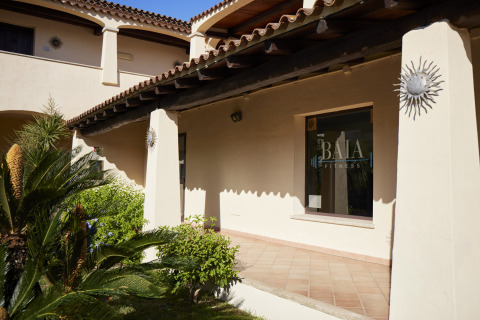 Vista exterior del Centro Vacanze Isuledda en Cerdeña, Italia, con el letrero del gimnasio BAIA FITNESS.