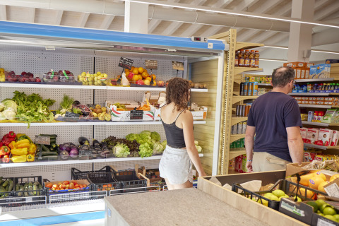 Dos personas compran frutas y verduras frescas en un pequeño supermercado en Cerdeña, Italia.