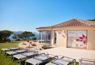 Udendørs afslapningsområde med liggestole og udsigt til havet ved Centro Vacanze Isuledda i Sardinien.