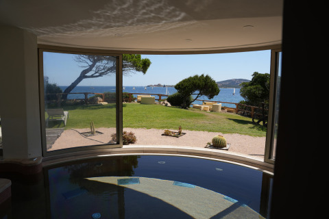 Vista de jardín y mar desde una sala con grandes ventanales en Centro Vacanze Isuledda, Cerdeña, Italia.