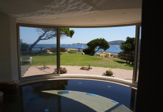 Vista su giardino e mare da una stanza con grandi finestre al Centro Vacanze Isuledda, Sardegna, Italia.