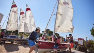Huéspedes preparan veleros en Centro Vacanze Isuledda, un parque vacacional en Cerdeña, Italia, bajo el sol.