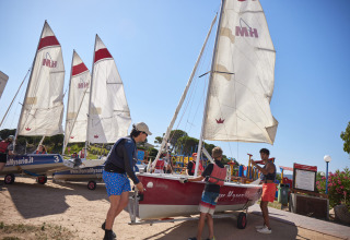 Guests prepare sailboats at Centro Vacanze Isuledda holiday park in Sardinia, Italy, on a sunny day.