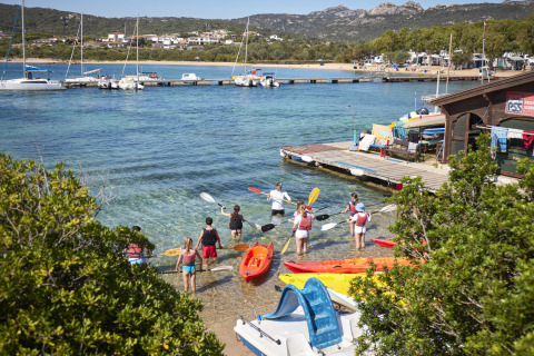Personas preparándose para hacer kayak en la playa de Centro Vacanze Isuledda, Cerdeña, Italia.