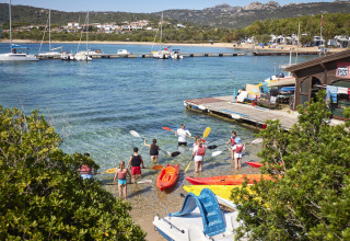 Folk gør sig klar til kajaksejlads ved en strand på Centro Vacanze Isuledda, Sardinien, Italien.