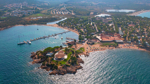 Vista aérea del Centro Vacanze Isuledda en Cerdeña, Italia, con playas, vegetación y puerto deportivo.