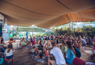 Familier og børn deltager i et udendørs arrangement under en overdækket pavillon i Holiday Park Ackersate.