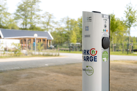 Estación de carga para coches eléctricos en Holiday Park Ackersate, Gelderland, Países Bajos, con edificio cercano.