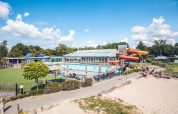 Udsigt over swimmingpoolen og vandrutsjebaner på Holiday Park Ackersate i Gelderland, Holland, under en blå himmel.