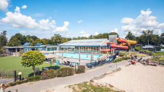 Uitzicht op het zwembad, de waterglijbanen en het loungegedeelte bij Holiday Park Ackersate in Gelderland.