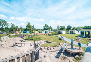 Børnevenligt ferieparkområde med legeplads og farverige hytter i Holiday Park Ackersate, Gelderland, Holland.