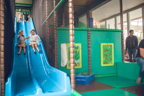 Niños jugando en un tobogán azul interior en Holiday Park Ackersate, un parque de vacaciones en Gelderland, Países Bajos.