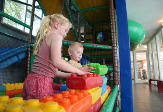To børn leger med store byggeklodser i et indendørs legeområde i Holiday Park Ackersate, Gelderland.