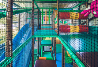 Indendørs legeplads med farverige klatrestrukturer og net i Holiday Park Ackersate, Gelderland, Holland.