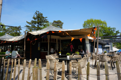 Zona de cafetería al aire libre en Holiday Park Ackersate, Gelderland, Países Bajos, con mesas y sillas.