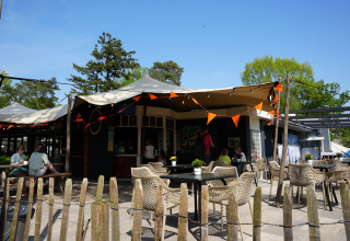 Udendørs caféområde i Holiday Park Ackersate, Gelderland, Holland, med borde, stole og solsejl.