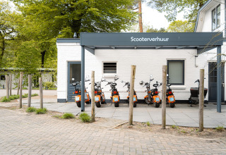 Scootere til leje ved et hvidt hus i et grønt område i Holiday Park Ackersate, Gelderland, Holland.
