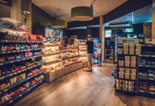 Supermarked i Holiday Park Ackersate, Gelderland, Holland med gæster, der vælger bagværk og snacks.
