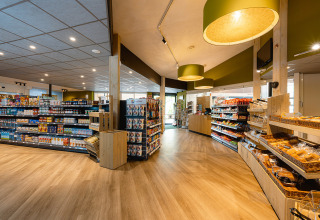 Bright supermarket interior at Holiday Park Ackersate, Gelderland, Netherlands, with shelves stocked with groceries.