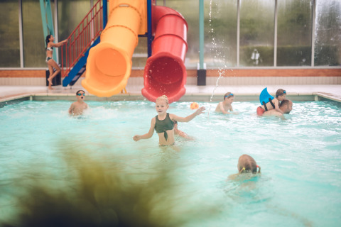 Niños juegan y nadan en una piscina cubierta con toboganes en Holiday Park Ackersate en Gelderland, Países Bajos.