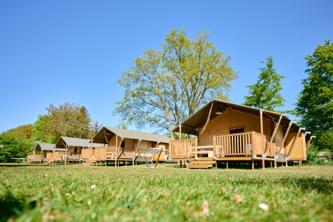 Houten lodges met canvasdaken op Holiday Resort de Bronzen Emmer in Drenthe, Nederland, bij zonnig weer.