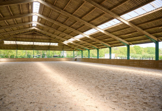 Indendørs ridehal med sandbund og trætag i ferieparken De Bronzen Emmer, Drenthe, Holland.