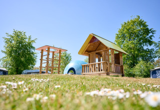 Playground with wooden playhouse and climbing structure at de Bronzen Emmer holiday park in Drenthe, Netherlands.