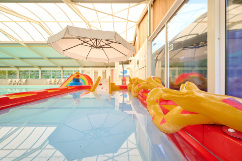 Piscina cubierta con área de juegos colorida y sombrilla en Holiday Resort de Bronzen Emmer en Drenthe, Países Bajos.