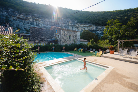 Niños disfrutan de la piscina en Medrose Camping con tumbonas y montañas en Auvergne-Rhône-Alpes, Francia.