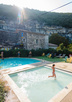 Niños disfrutan de la piscina en Medrose Camping con tumbonas y montañas en Auvergne-Rhône-Alpes, Francia.